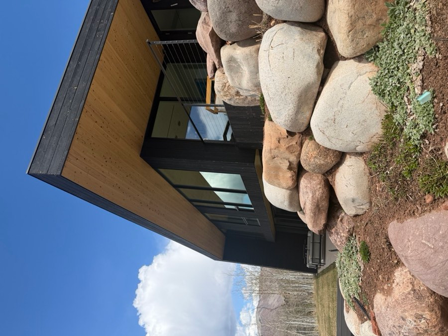 Contemporary home exterior with large boulder landscaping and mountain sky