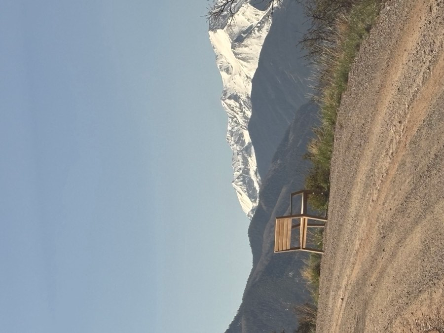 Mountain peak with snow and rocky terrain, viewed from a road