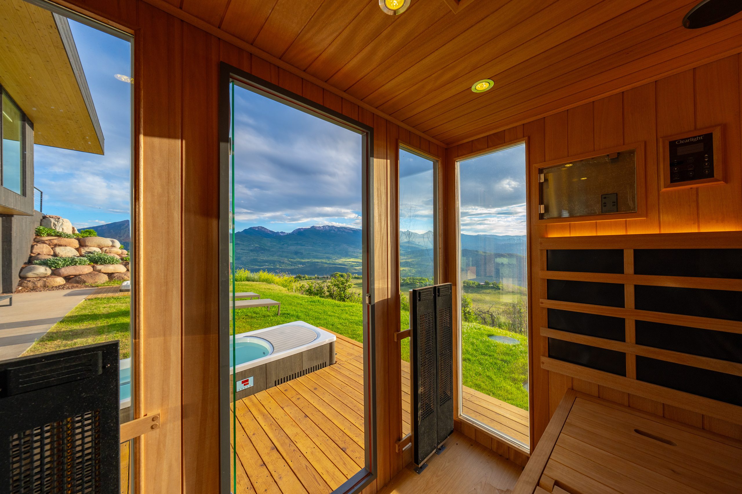 The sauna — glass to the deck, the cold plunge, and the valley beyond.