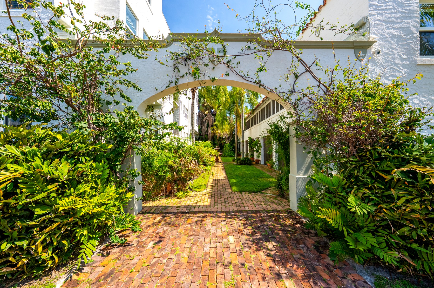 The arched rear entry to the building. Brick path, palms, lush landscaping, you walk through to reach your backdoor.