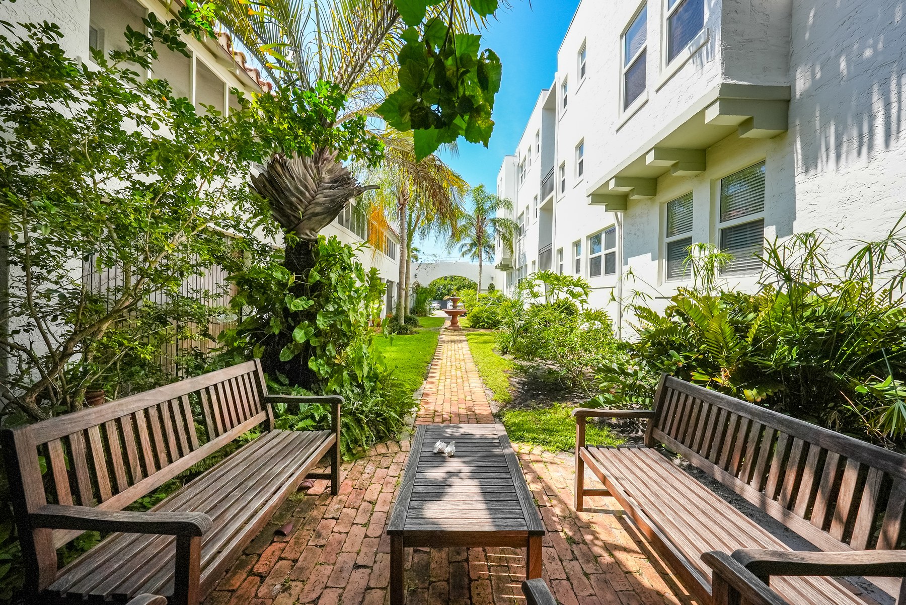 The interior courtyard today. Brick path, palms, and benches the residents actually sit on.
