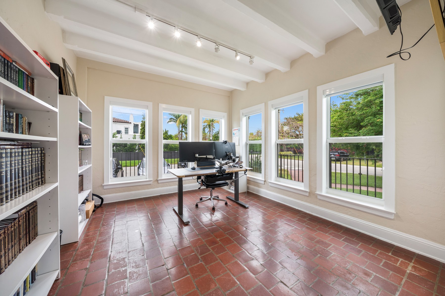 The third bedroom in Unit 1 — three walls of windows and the feeling of being in a house. The current owner uses it as an office. Either way, it is the room people walk into and stop talking.