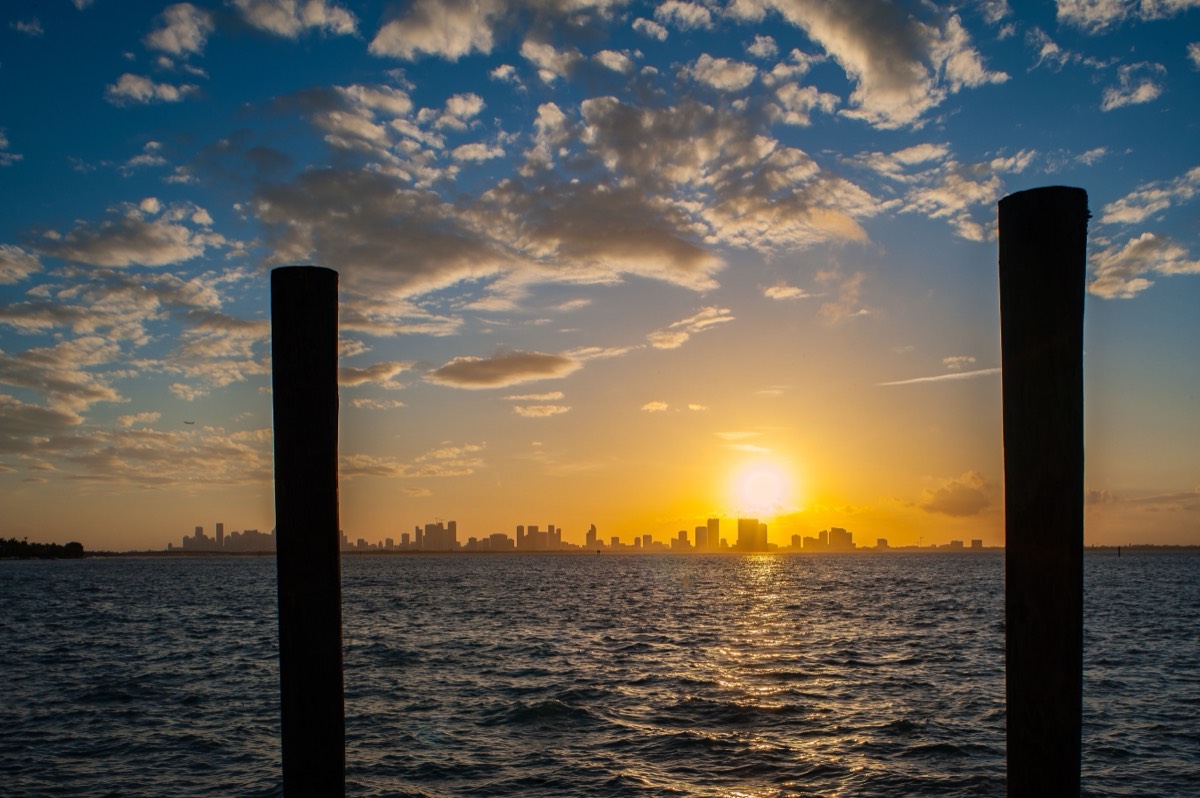 The view from 5410 North Bay Road — sunset over Biscayne Bay with downtown Miami glowing in the distance.